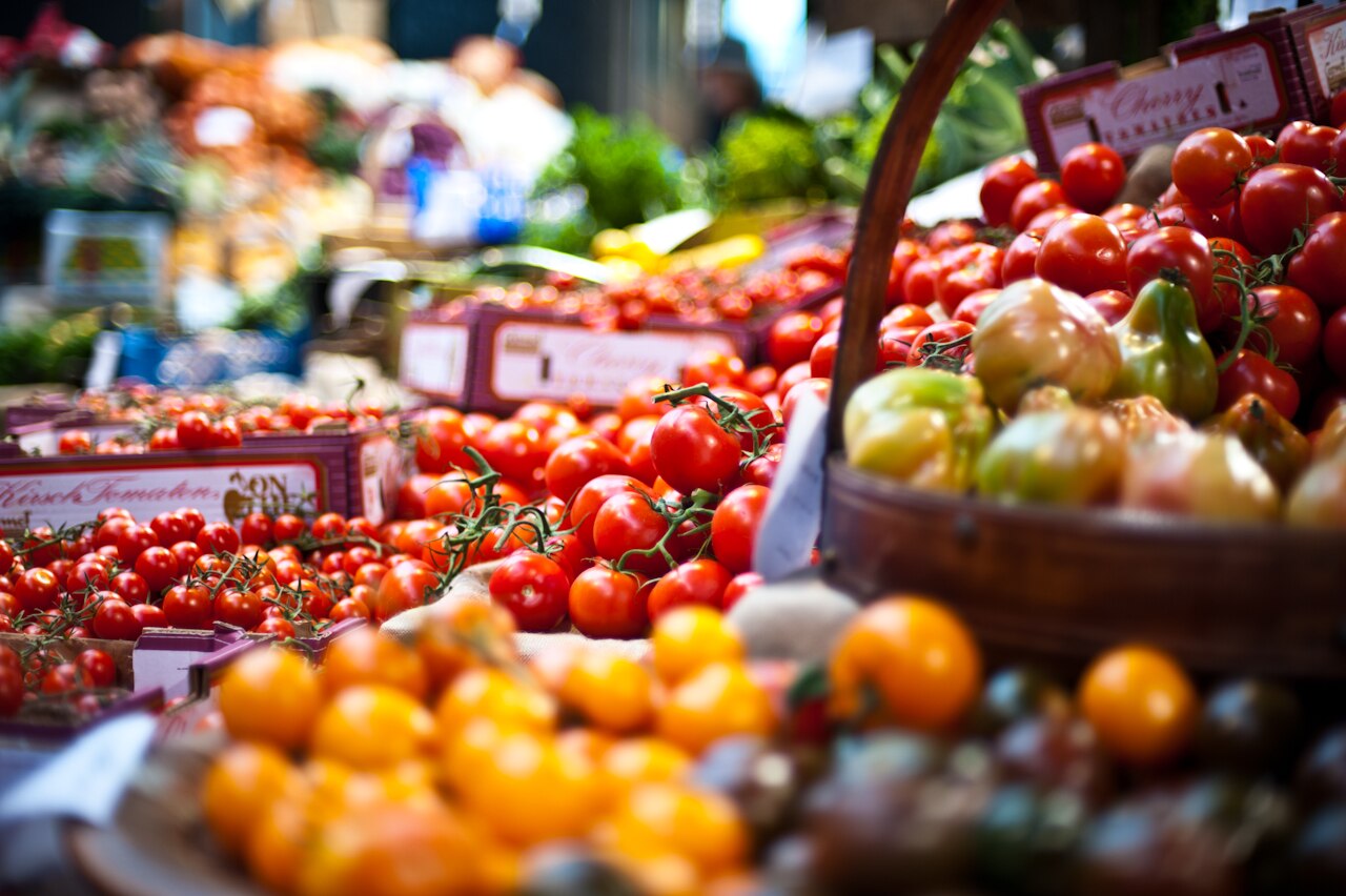 A market stall stacked with crates of fresh tomatoes